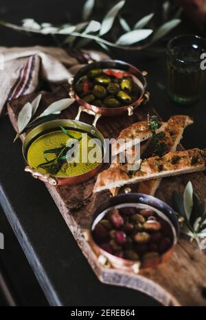 Olives grecques marinées, huile d'olive et tranches de focaccia herbed sur bois rustique, foyer sélectif. Plateau de hors-d'œuvre méditerranéen traditionnel Banque D'Images