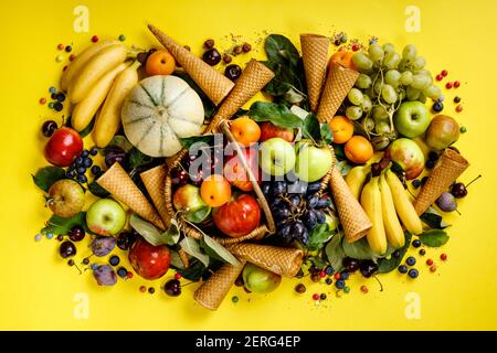 Ponce plate de fruits et de baies et de cônes de crème glacée sur fond jaune. Vue de dessus. Banque D'Images