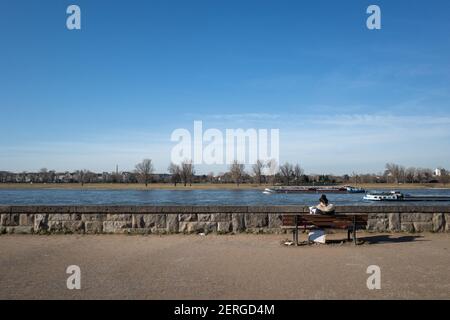 Une femme s'assoit sur un banc sur la promenade du Rheinpark Golzheim, grand parc long le long du fleuve Rhin à Düsseldorf, en Allemagne Banque D'Images