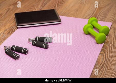 Tapis de fitness, haltères, extenseur et ordinateur portable pour les entraînements en ligne à la maison. Concept d'apprentissage en ligne en relation avec la pandémie Banque D'Images