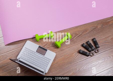 Tapis de fitness, haltères, extenseur et ordinateur portable pour les entraînements en ligne à la maison. Concept d'apprentissage en ligne en relation avec la pandémie Banque D'Images