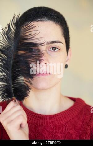 Belle, jeune femme couvrant le visage avec des plumes noires Banque D'Images