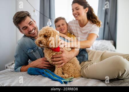 Joyeux jeune famille sympathique passer des moments de plaisir ensemble et de se câliner avec leur animal de compagnie à la maison Banque D'Images