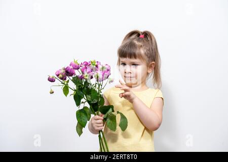 petite fille dans un chemisier jaune avec des fleurs décolorées. Banque D'Images