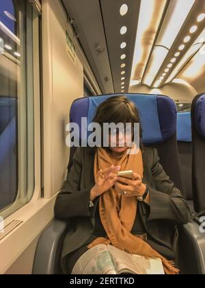 Femme d'affaires utilisant un Smart Phone et assis dans un train à Monte Carlo, Monaco. Banque D'Images