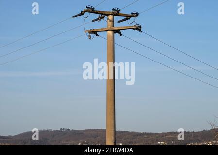 Poteau électrique en béton avec isolants en céramique et lignes de tension, en fond bleu ciel avec ciel bleu. Banque D'Images