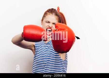 un sportif agressif avec des gants de boxe et un t-shirt rayé sur un arrière-plan clair Banque D'Images