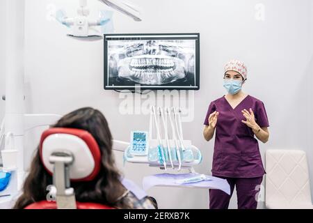 Photo de la femme dentiste montrant une radiographie de sa jeune patiente. Banque D'Images