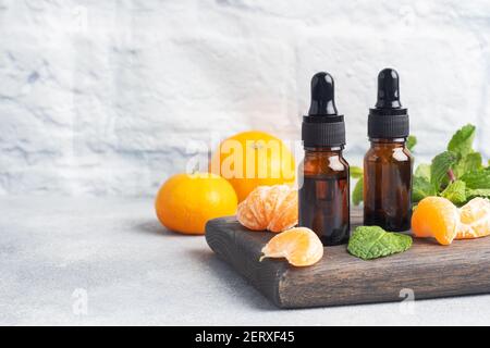 Huile de mandarine aromatique dans une bulle sombre, huile cosmétique de mandarine sur fond gris clair, espace de copie Banque D'Images