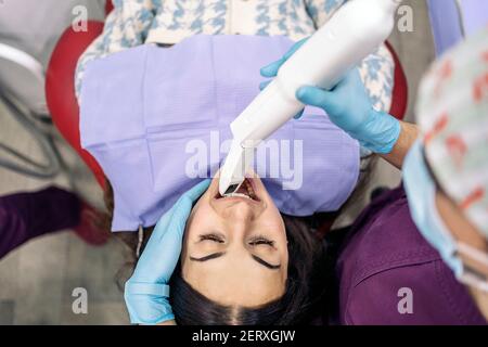 Photo d'une femme dentiste non reconnue portant des gants en latex pour examiner un patient. Banque D'Images