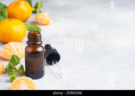 Huile de mandarine aromatique dans une bulle sombre, huile cosmétique de mandarine sur fond gris clair, espace de copie Banque D'Images