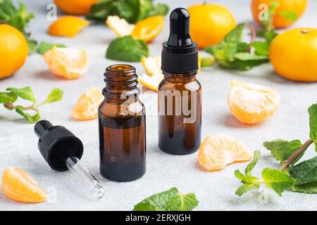 Huile de mandarine aromatique dans une bulle sombre, huile cosmétique de mandarine sur fond gris clair, espace de copie Banque D'Images