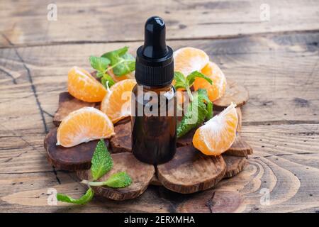 Huile de mandarine aromatique dans une bulle sombre, huile cosmétique de mandarine sur fond de bois, espace de copie Banque D'Images