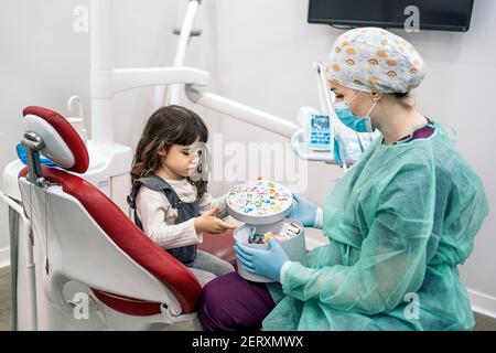 Photo de la femme dentiste portant un masque facial travaillant avec un jeune patient. Banque D'Images