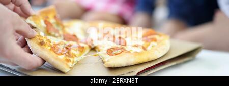 Sur la table se trouve la pizza, coupé en morceaux la main de l'homme tient deux piles Banque D'Images