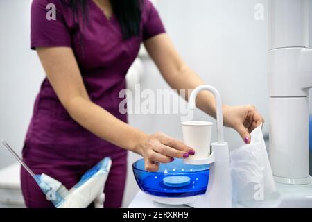 Photo de l'employé non reconnu en clinique dentaire utilisant un distributeur d'eau. Banque D'Images