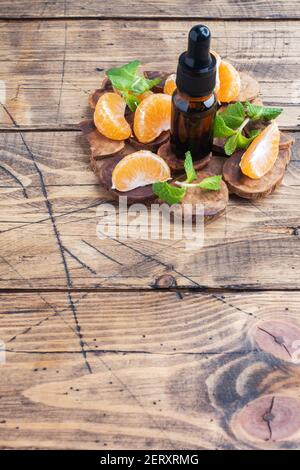 Huile de mandarine aromatique dans une bulle sombre, huile cosmétique de mandarine sur fond de bois, espace de copie Banque D'Images
