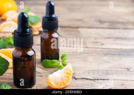 Huile de mandarine aromatique dans une bulle sombre, huile cosmétique de mandarine sur fond de bois, espace de copie Banque D'Images