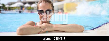 Femme dans des lunettes de soleil près du côté au parc aquatique. Banque D'Images