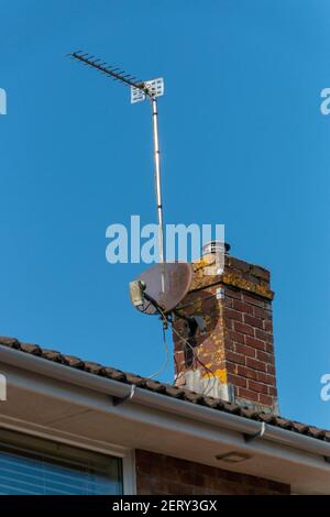 une vue rapprochée d'une cheminée en briques avec un ancienne parabole satellite et son support métallique un toit résidentiel Banque D'Images