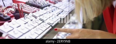 La femme examine et choisit les bijoux en magasin. Banque D'Images