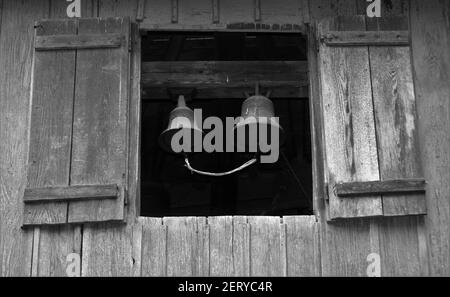 Un cliché en échelle de gris de deux cloches dans une ancienne grange Banque D'Images