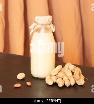 Bouteille en verre avec lait d'arachide et arachides dans la coquille. Lait sans lactose, végétarisme. Banque D'Images