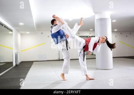 Échange de coups de pied élevés pendant l'entraînement du taekwondo entre deux combattants Banque D'Images