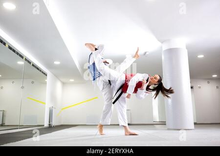 Échange de coups de pied élevés pendant l'entraînement du taekwondo entre deux combattants Banque D'Images