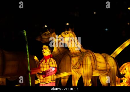 Festival des lanternes chinoises au parc de Limanski. Un homme avec une écharpe rouge, tenant un bâton de bambou, se tient à côté d'une calèche tirée par des chevaux. Banque D'Images