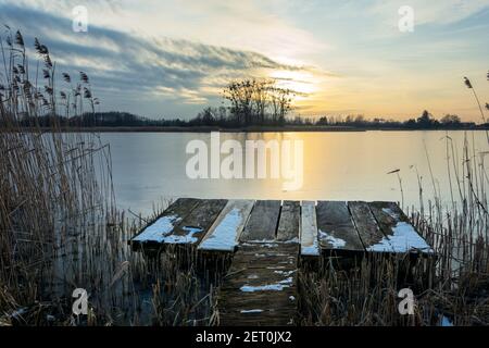 Une plate-forme de pêche dans les roseaux et coucher de soleil sur un lac calme, paysage d'hiver, Stankow, Lubelskie, Pologne Banque D'Images