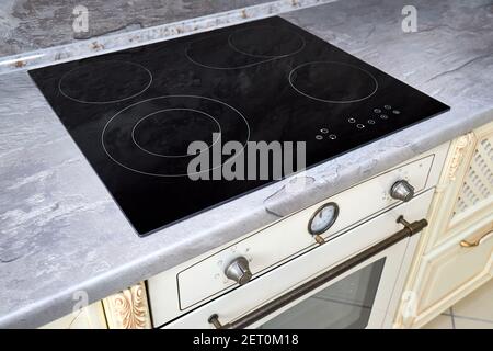 Cuisine moderne intérieur luxueux avec plaque de cuisson à induction noire ou électrique cuisinière avec surface en céramique avec comptoir en marbre et décoration murale Banque D'Images