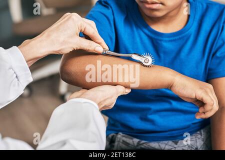 Gros plan du contrôle de la main du petit garçon à l'aide de la roue d'aiguille neurologique dans une clinique neurologique Banque D'Images