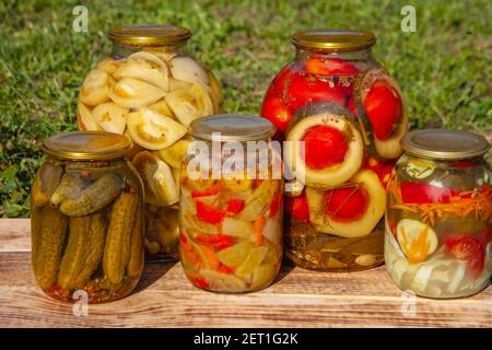 Des cornichons faits maison en pots, des aliments rustiques et des collations sont préparés sur des planches sur fond d'herbe. En-cas traditionnel russe Banque D'Images