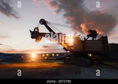 Silhouette d'un creuseur mécanique dans une mine de minerai de fer au coucher du soleil, en Thaïlande Banque D'Images