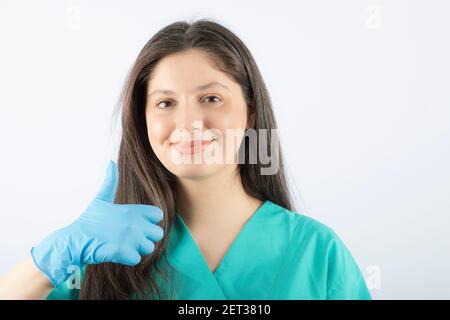 Portrait d'une jeune femme médecin en uniforme vert montrant un pouce vers le haut Banque D'Images