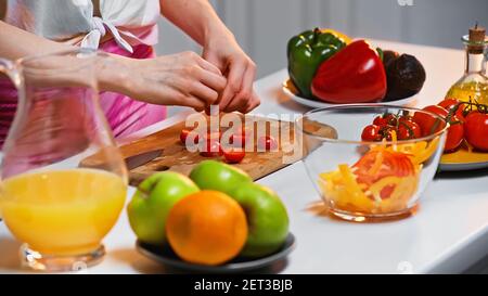 vue rognée de la femme près des tomates cerises et d'autres légumes sur une table de cuisine Banque D'Images