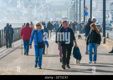 Sidmouth, Devon, Royaume-Uni. 1er mars 2021. Météo Royaume-Uni. Le front de mer est animé par les gens qui profitent du soleil de printemps tout en s'exerçant à Sidmouth à Devon dans un après-midi ensoleillé et chaud avec un ciel bleu clair le premier jour du printemps météorologique. Crédit photo : Graham Hunt/Alamy Live News. Banque D'Images
