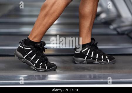 Gros plan des jambes d'homme noir marchant sur un tapis roulant Banque D'Images