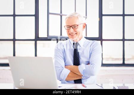 Photo d'un homme d'affaires assis derrière son ordinateur portable et ayant une discussion et une réunion en ligne en vidéoconférence avec son collègue. Banque D'Images