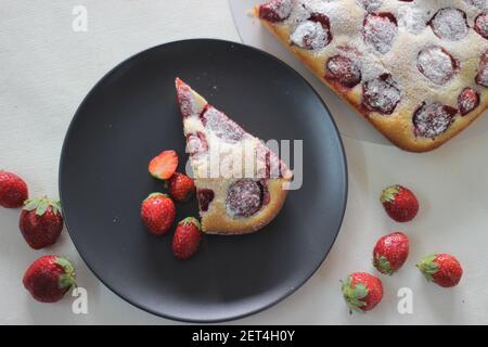 Gâteau aux fraises maison. Un simple gâteau jaune avec beaucoup de fraises fraîches et de sucre en poudre saupoudrés sur le dessus. Prise de vue sur fond blanc Banque D'Images