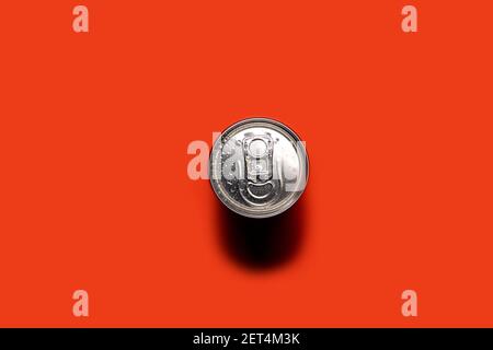 Boîte en aluminium sur fond rouge-orange, avec gouttes d'eau, vue de dessus. Banque D'Images