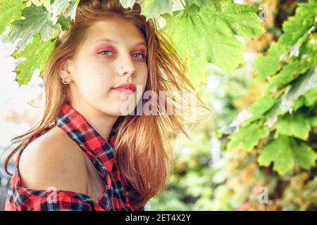 Jeune femme attrayante sur fond de feuilles vertes. Portrait d'une belle fille de 16 ans Banque D'Images