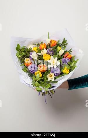 Bouquets de jacinthes bleues, tulipes jaune et orange et fleurs de jonquilles blanches à la main sur blanc Banque D'Images