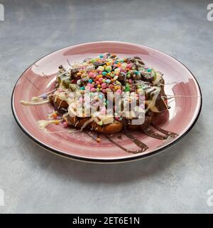 Une délicieuse gaufre servie avec une assiette rose sur un arrière-plan gris Banque D'Images