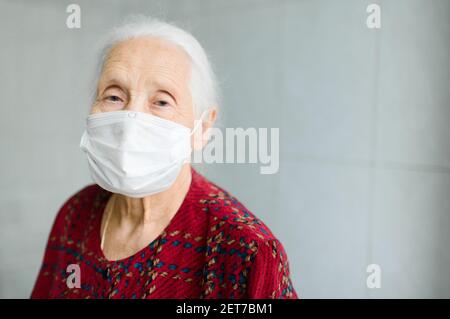 portrait d'une femme âgée de 70-80 ans avec des cheveux gris dans un masque médical. Banque D'Images