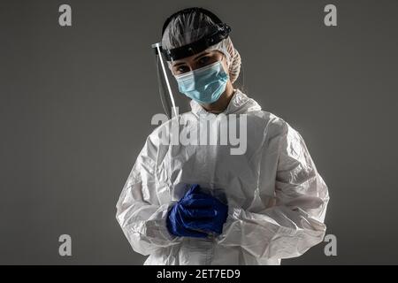 Concept de santé. Vue latérale de la femme en costume blanc hazmat, lunettes et masque respiratoire isolés sur fond bleu avec espace de copie Banque D'Images