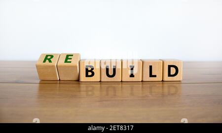 Temps de reconstruction du symbole. A tourné des cubes en bois et a changé le mot « construire » en « construire ». Belle table en bois, fond blanc. Affaires, construire ou re Banque D'Images