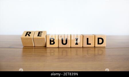 Temps de reconstruction du symbole. A tourné des cubes en bois et a changé le mot « construire » en « construire ». Belle table en bois, fond blanc. Affaires, construire ou re Banque D'Images