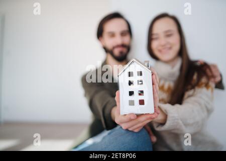Jeunes propriétaires de couple tenant modèle de maison, déménagement, nouveau concept de maison et de relocalisation. Banque D'Images